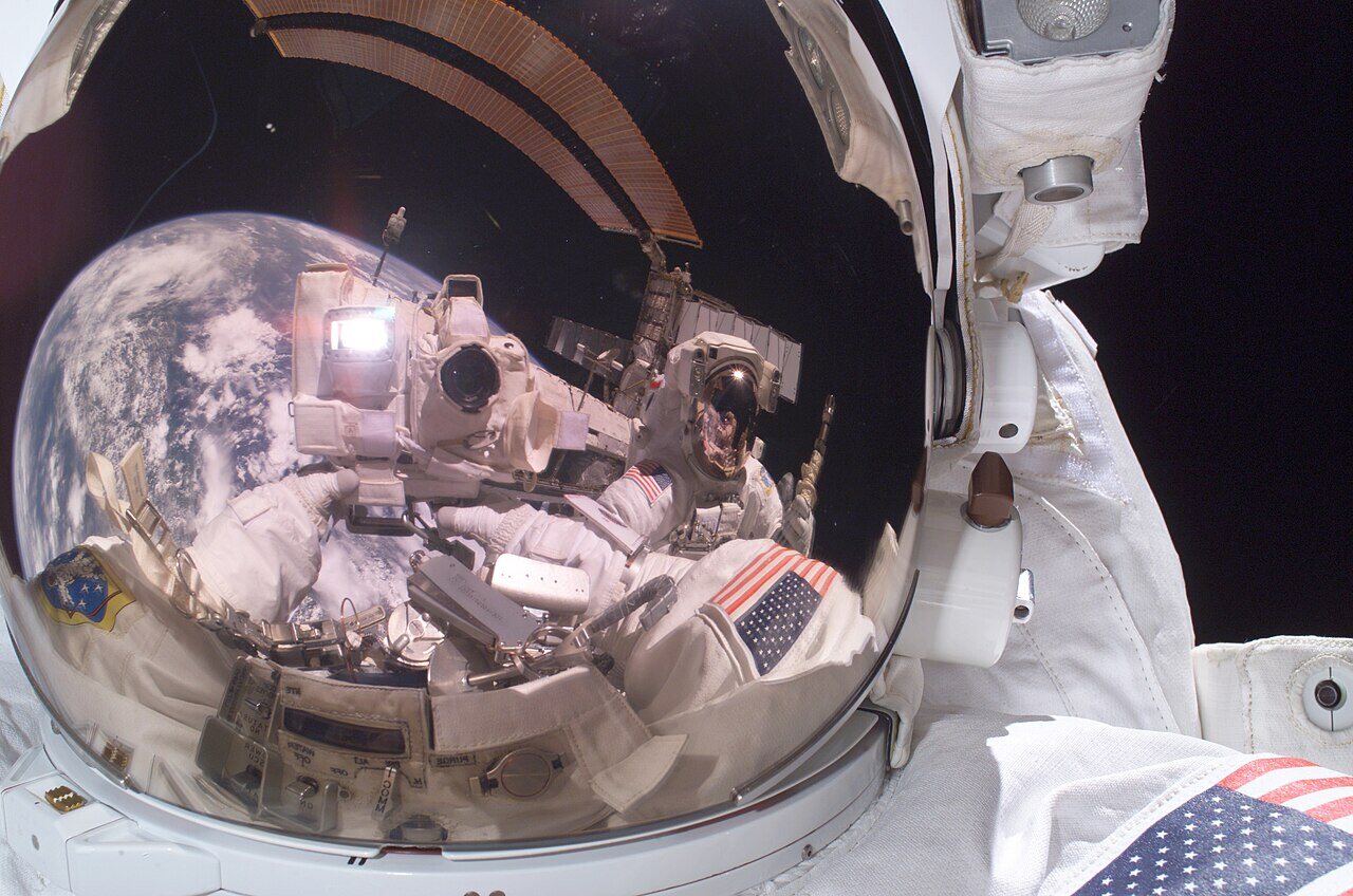A former Commander of the International Space Station on a spacewalk, the Earth reflected in his visor