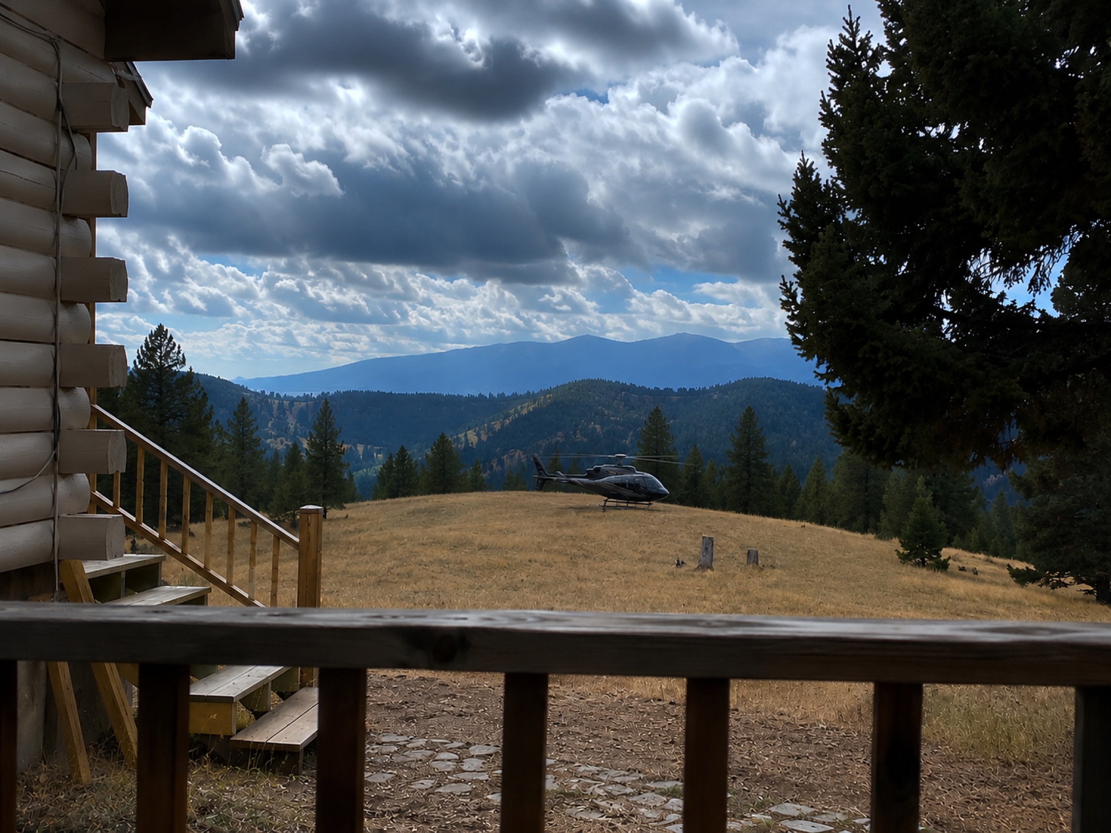 A private helicopter at rest on the meadow at Sweetwater Ranch, Gold Creek, Montana, with forested mountains beyond